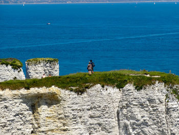 People standing on top of cliff against sea