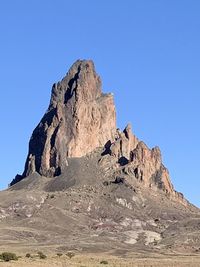 Rock formations on landscape against clear blue sky