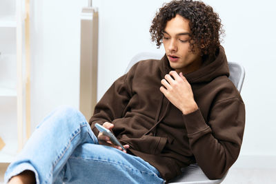 Young woman using mobile phone while sitting on sofa at home