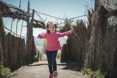 Full length of cute girl walking on footpath amidst plants