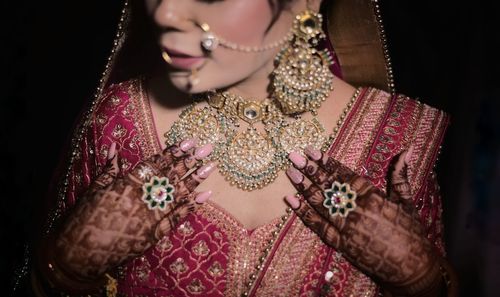 Photo of young woman wearing traditional clothing on their wedding and show their necklace 