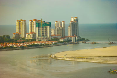 Sea by buildings against sky in city