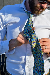 Midsection of man holding umbrella standing against blue wall