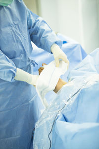 Cropped image of surgeon wrapping bandage on patient wounded foot