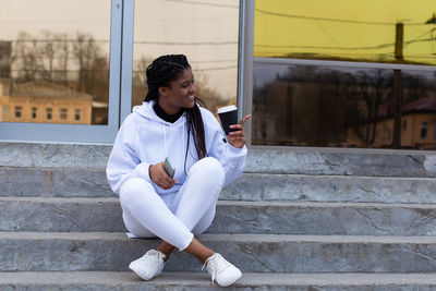 Young man using mobile phone while sitting on staircase