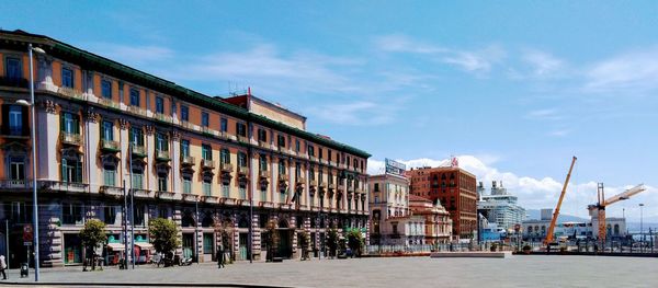 Buildings by road against sky in city