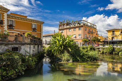 Buildings by river against sky