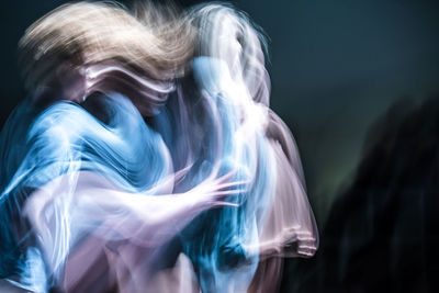 Blurred motion of dancer dancing against black background