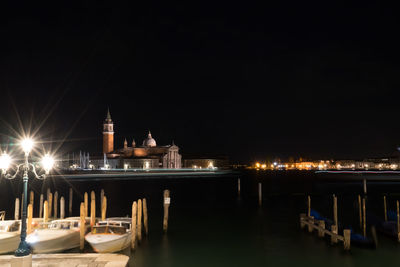 Grand canal by illuminated church of san giorgio maggiore against clear sky at night