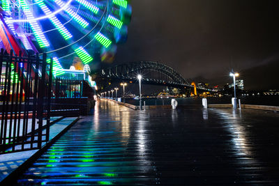 Illuminated bridge over river in city at night