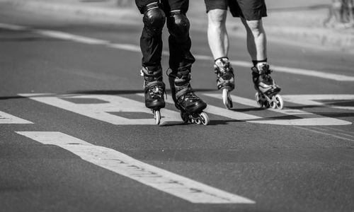 Low section of people rollerskating on road