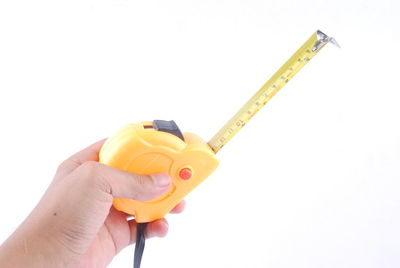 Close-up of hand holding yellow object against white background