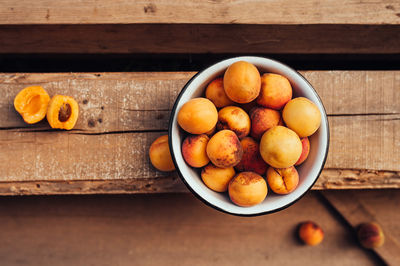 Ripe juicy homemade apricots with cracks and flaws in the plate and scattered on wooden boards