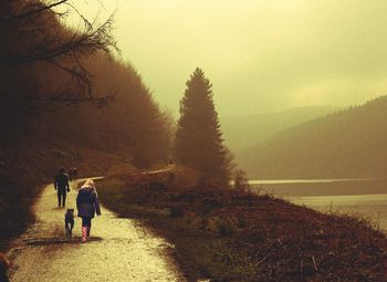 Rear view of people walking on landscape against clear sky