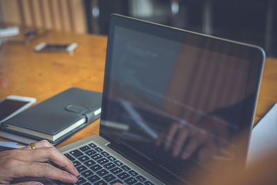 Cropped hand of person using laptop in office