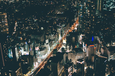 High angle view of illuminated street amidst buildings at night