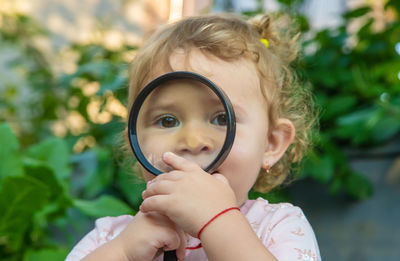 Portrait of young woman holding magnifying glass