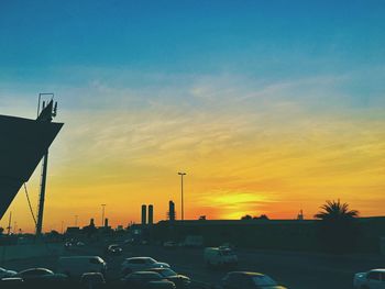 Cars on road against sky during sunset