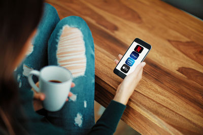 High angle view of woman holding coffee cup on table