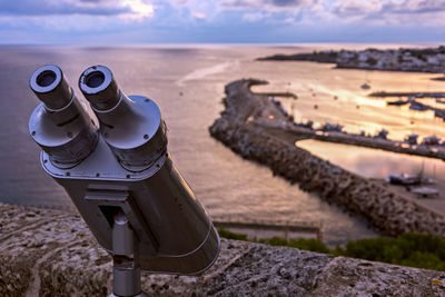 Close-up of coin-operated binoculars by sea against sky