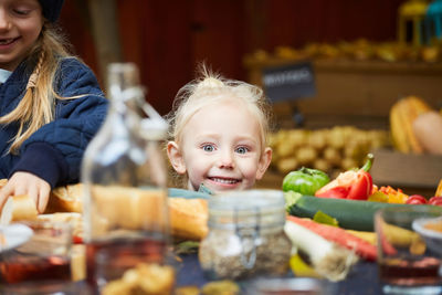 Portrait of smiling girl sitting by female sibling at table in back yard