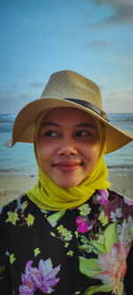 Portrait of woman wearing hat standing at beach