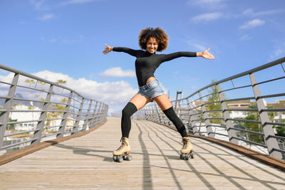 Portrait of woman roller skating on footbridge in city