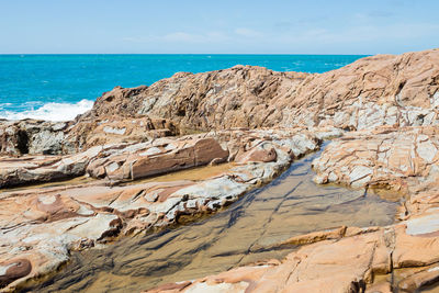 Rock formations on beach against sky