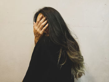 Portrait of woman standing against wall