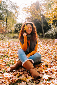 Full length of smiling young woman sitting on land