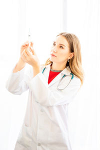 Young woman with arms raised standing against white background