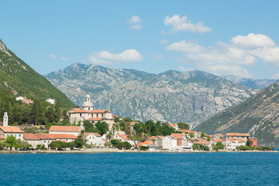 Houses by sea and mountains against sky at kotor bay against sky