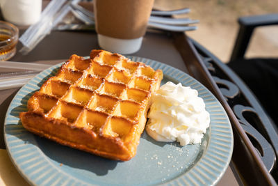 Close-up of waffle with cream served in plate on table