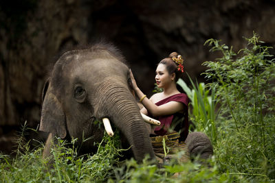 Smiling girl petting elephant in forest