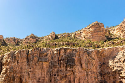 Rock formations on landscape against clear blue sky