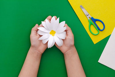 Cropped hands of woman holding heart shape against blue background