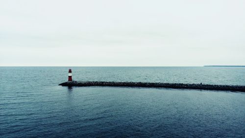 Rear view of man standing in sea against sky