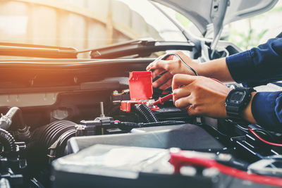 Cropped hands of mechanic repairing car in garage