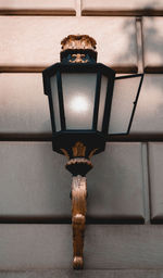 Low angle view of illuminated lamp hanging against wall