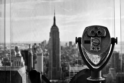 Close-up of coin-operated binoculars against cityscape