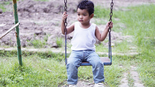 Portrait of boy sitting on swing at playground