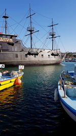 Boats moored at harbor against clear sky