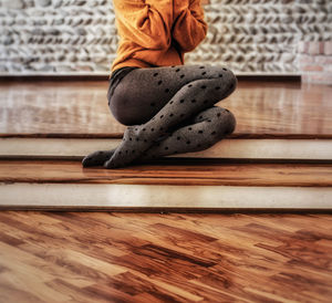 Low section of woman sitting on wooden floor