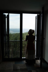 Rear view of woman looking through window