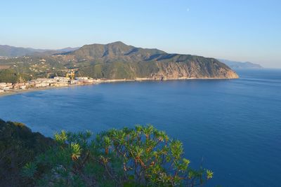 Scenic view of sea and mountains against clear blue sky