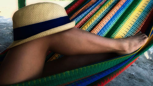 Low section of woman with hat relaxing on hammock