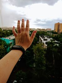 Close-up of man with hand against sky in city