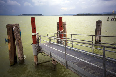 Wooden posts on sea against sky