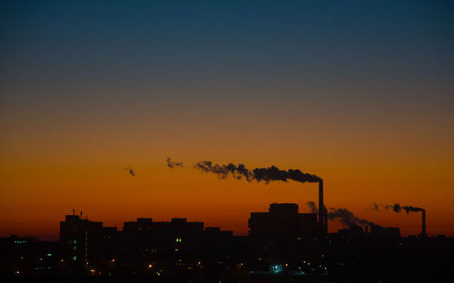Silhouette smoke emitting from factory against sky during sunset