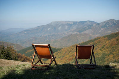 Chair on field against mountain range